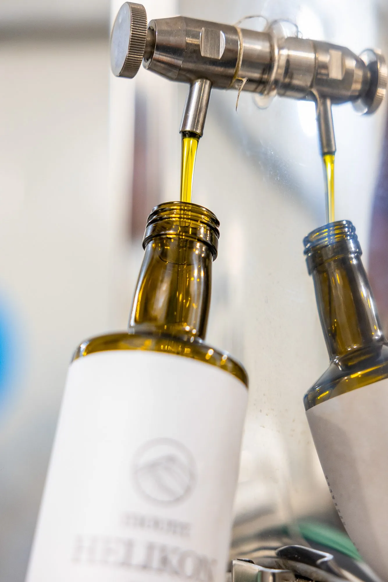 Two bottles filling with oil under the taps of the Kadmus bottling line